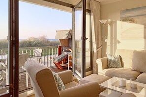 A balcony with a view of the beach, a sofa, a table with candles, and a chair. - Deichgraf 07, Direkter Meerblick aus Allen Drei Zimmern, 2 SZ, 2xbad, TG, Kamin (Börgerende-Rethwisch)