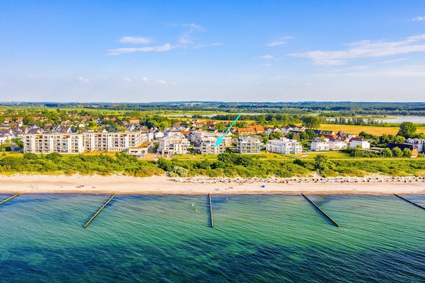 Una località costiera con spiaggia, edifici residenziali e una vista aperta sul mare.