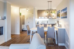 Una cucina moderna con zona pranzo, pavimento in legno e lampade a sospensione.