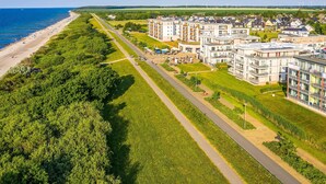 An aerial view of a coastal residential area with a beach, a road, and modern apartment buildings. - Deichgraf 07, Direkter Meerblick aus Allen Drei Zimmern, 2 SZ, 2xbad, TG, Kamin (Börgerende-Rethwisch)