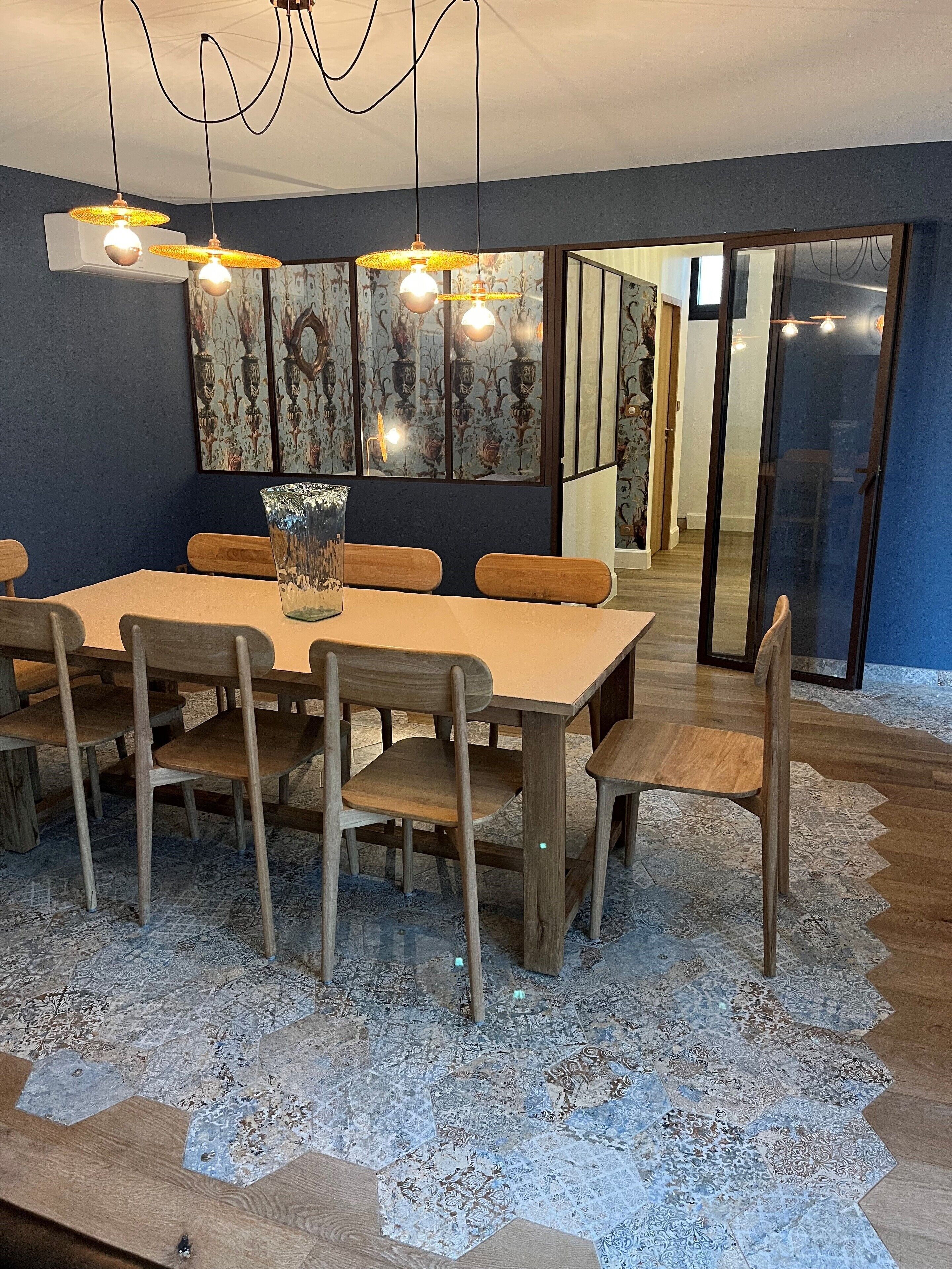 A dining area with a wooden table, chairs, and a patterned rug.