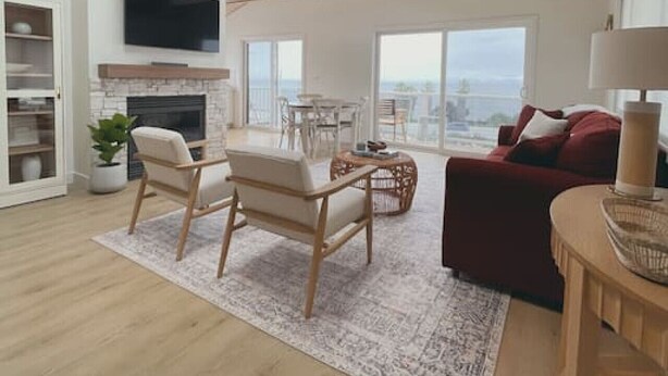 A spacious living room with a high ceiling, wooden beams, a fireplace, a television, and a large window offering a city view. - Summerland Ocean View no. 3 (Summerland)