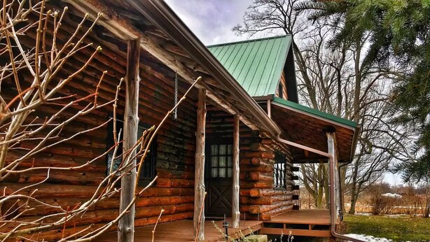 A log cabin with a wooden deck and a covered porch. - Authentic log cabin! (Youngstown)