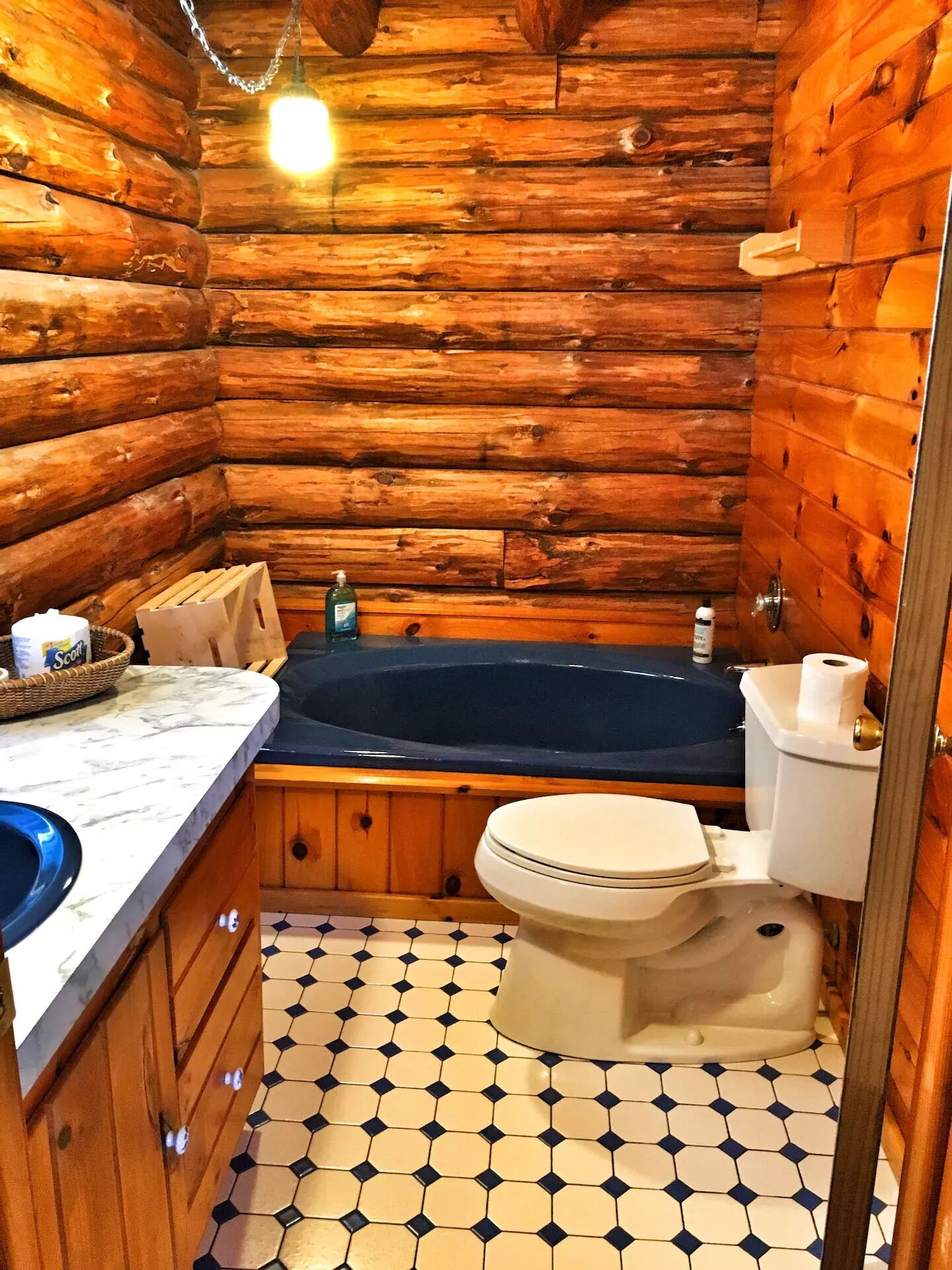 Een badkamer in een blokhut met houten inrichting, een bad, toilet en wastafel.