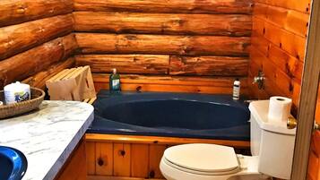 Een badkamer in een blokhut met houten inrichting, een bad, toilet en wastafel.