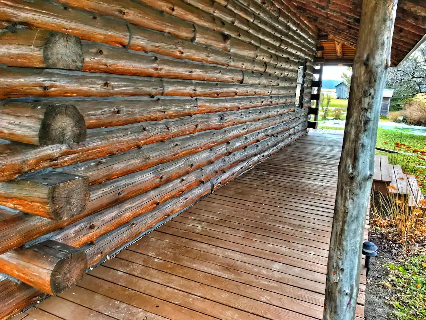 A log cabin with a wooden deck and a stone foundation.