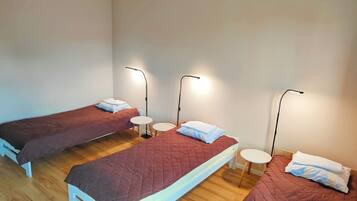 Una habitación con tres camas, cada una con una mesita de noche y una lámpara.