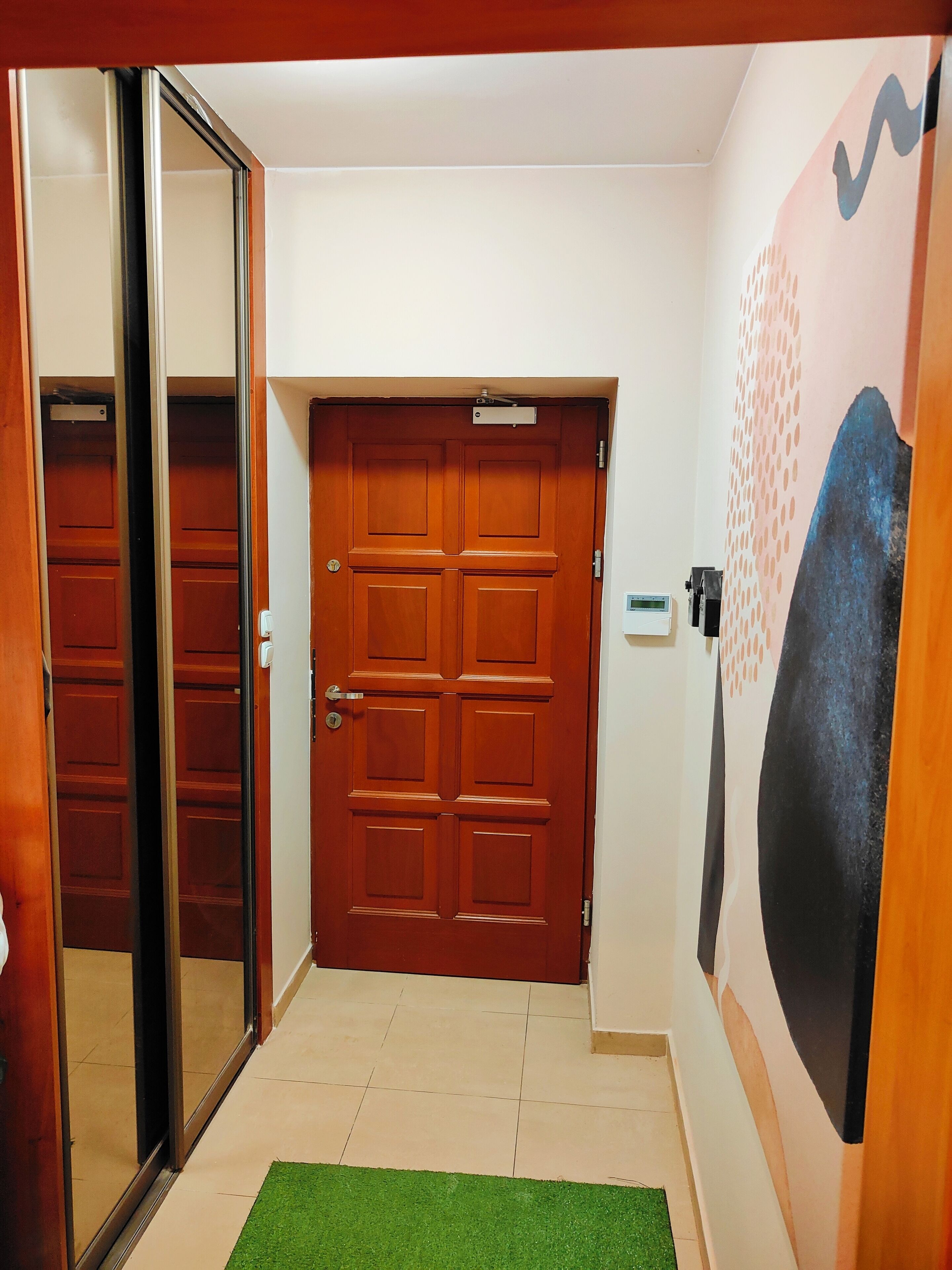 A hallway with a wooden door, a glass door, and a wall with a textured pattern.
