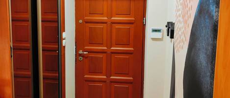 A hallway with a wooden door, a glass door, and a wall with a textured pattern.