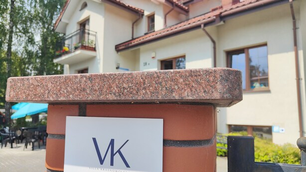 Une enseigne portant les lettres « VK » et le nom « Villa Krasnowolska », indiquant ainsi le nom de l’hôtel.