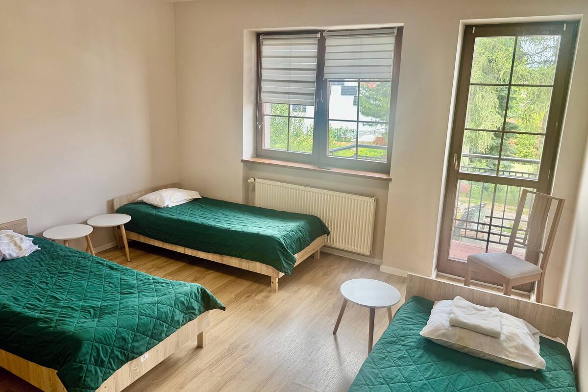 A dormitory room with two beds, a radiator, and two small tables.
