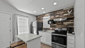 Una cocina moderna con armarios blancos, encimera de granito, electrodomésticos de acero inoxidable y un salpicadero de madera.