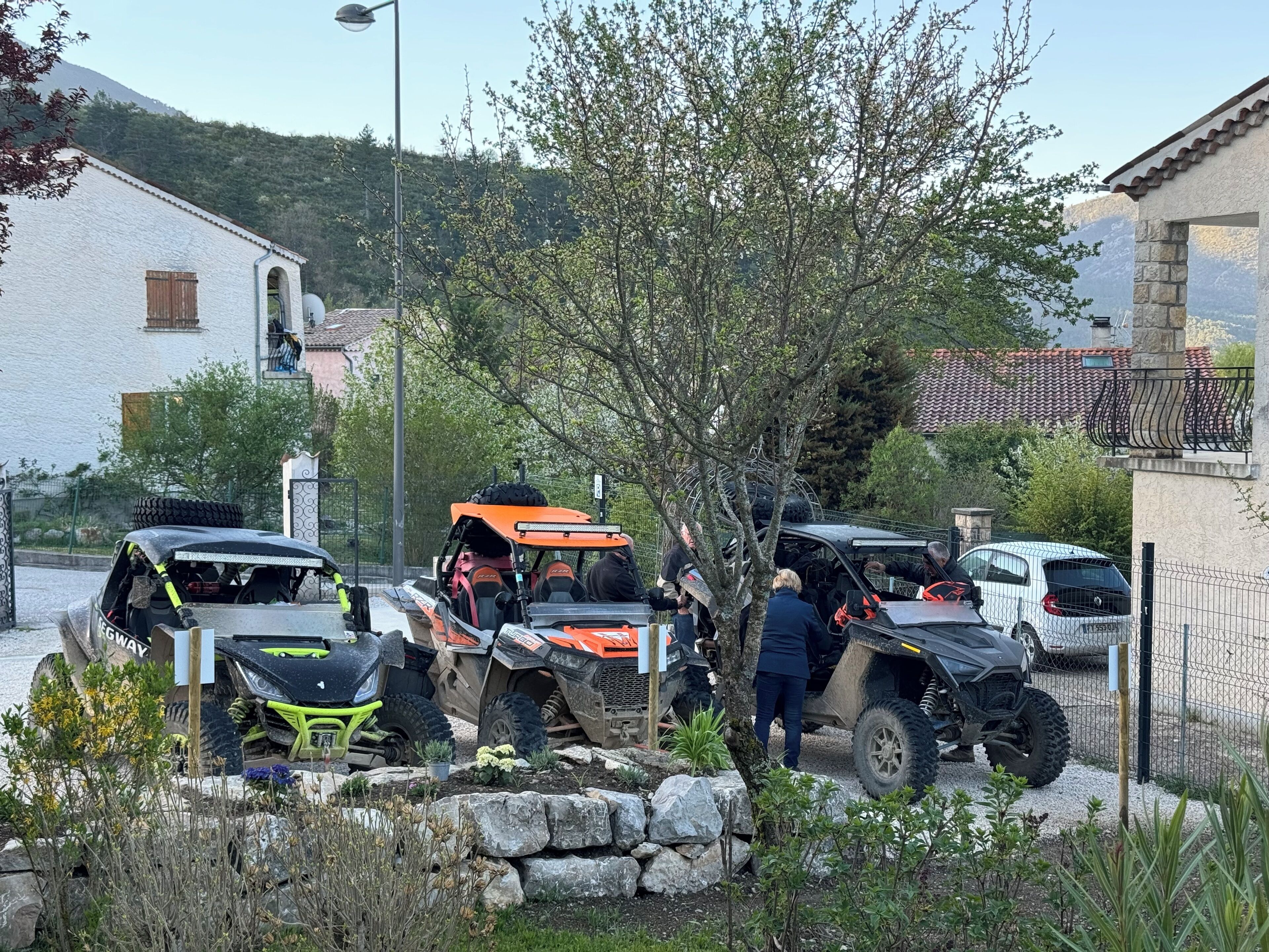 Un espace de stationnement où sont garés plusieurs véhicules tout-terrain, et où se trouve un mur en pierre.
