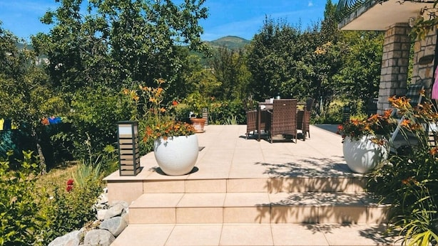 A paved pathway leading to a seating area with a table and chairs, surrounded by potted plants and a stone wall. - BNB Castellane (Castellane)
