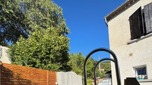 A swimming pool with a wooden deck, a stone wall, and a building with a window and shutters. - BNB Castellane (Castellane)