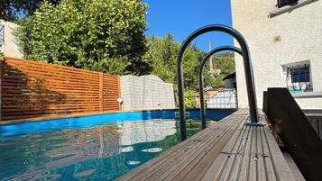 Una piscina al aire libre de temporada, sillones reclinables de piscina