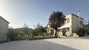 A stone building with a gravel driveway, a tree, and a mountain in the background. - BNB Castellane (Castellane)
