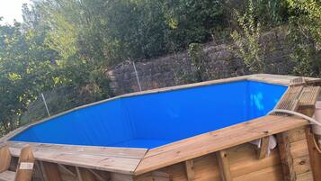 Een seizoensgebonden buitenzwembad, ligstoelen bij het zwembad