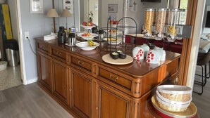 A kitchen with a wooden cabinet, a coffee station, and a fruit display. - BNB Castellane (Castellane)