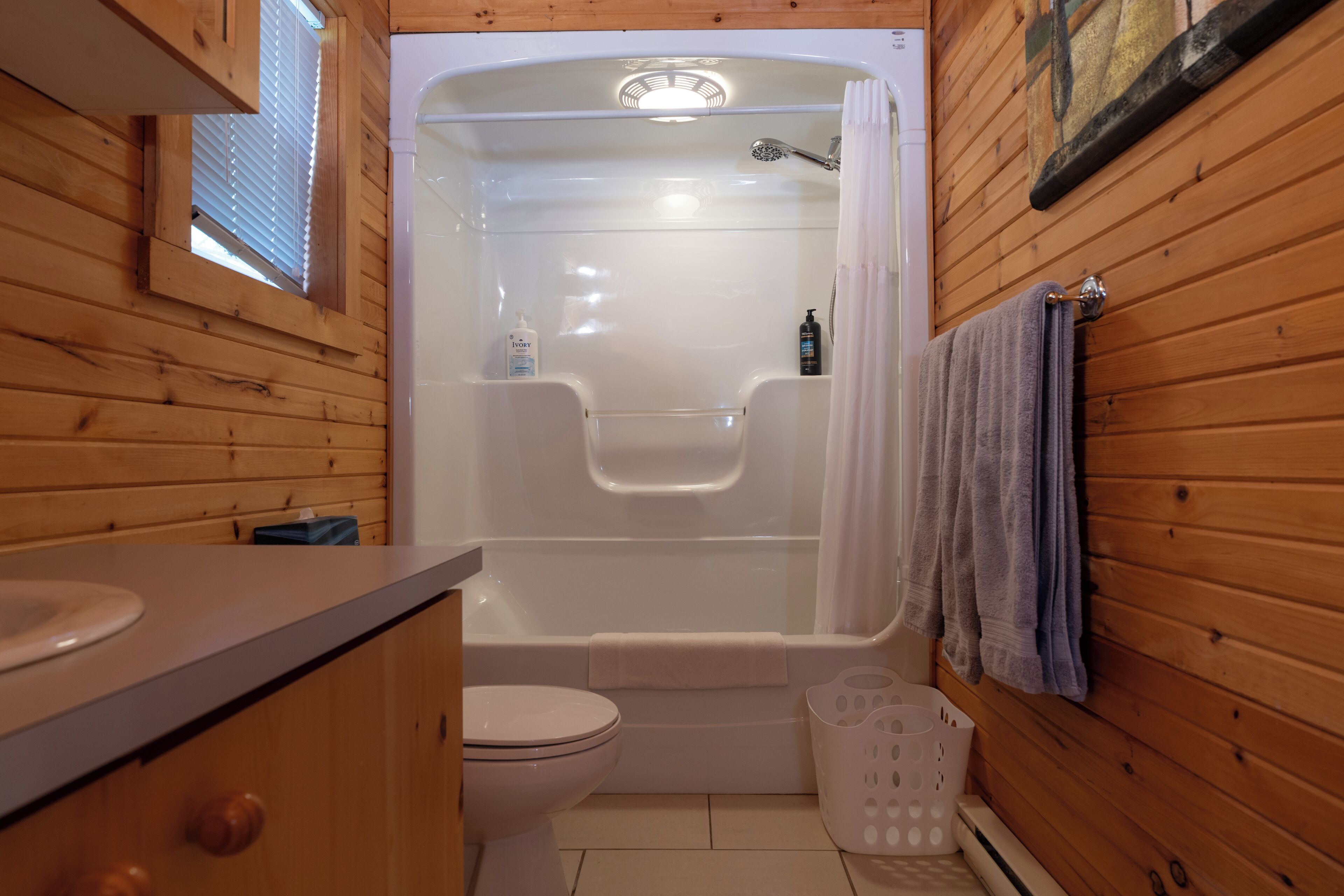 Baño de cabaña de madera con bañera, inodoro y lavamanos.
