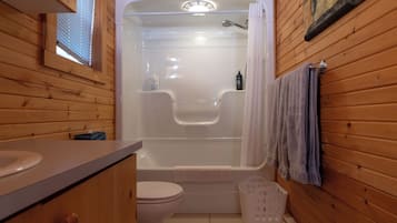 Baño de cabaña de madera con bañera, inodoro y lavamanos.