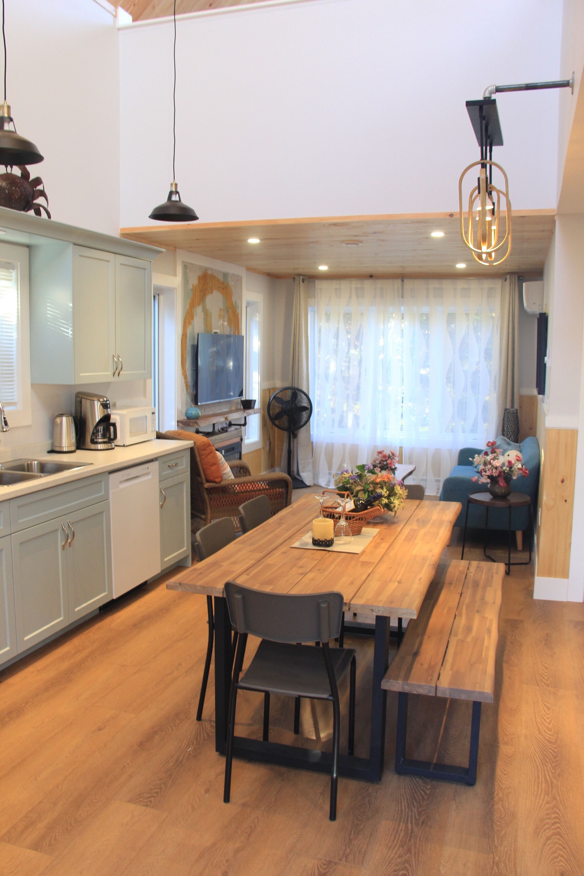 A modern kitchen with a wooden dining table, a built-in oven, and a microwave.