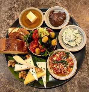 Une variété d’aliments, notamment du fromage, des noix, des olives et une salade, présentés sur une assiette.