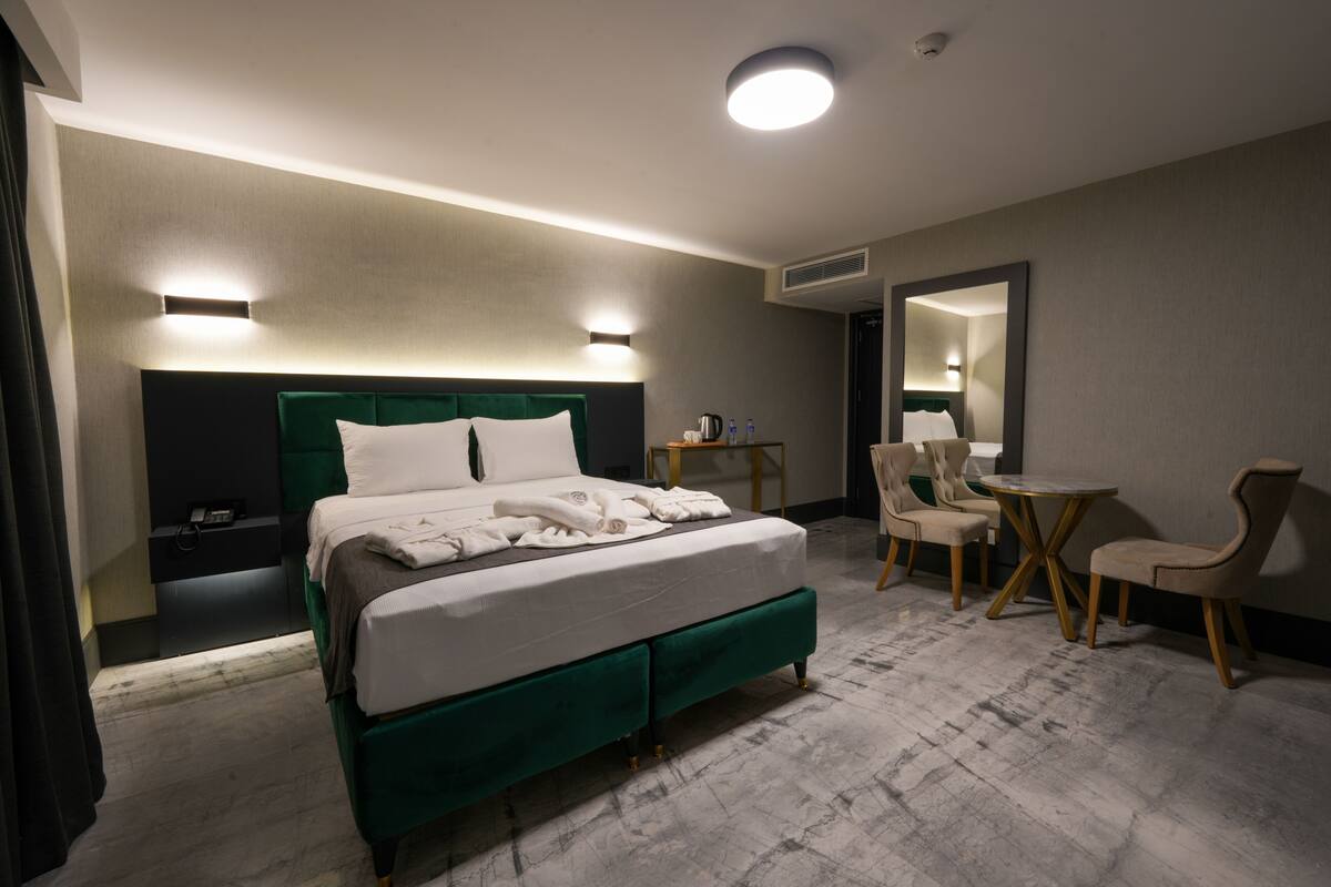 Una habitación de hotel con una cama grande, un escritorio, dos sillas y un espejo.