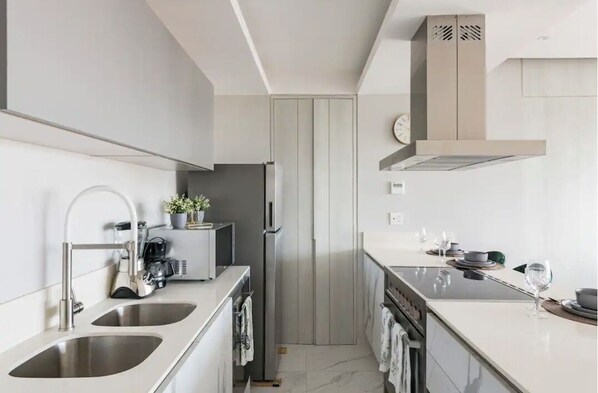 Una cocina moderna con electrodomésticos de acero inoxidable, horno empotrado y encimera con lavabo.