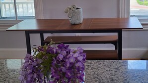 Una cocina con encimeras de granito, una mesa de madera y un florero con flores moradas.