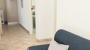 Sala de estar com sofá azul escuro, duas almofadas, parede branca e decoração amarela.