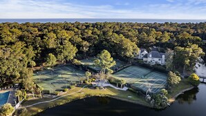 A tennis court complex with multiple courts, a swimming pool, and a large house surrounded by dense forest. - Hilton Head Island in Shipyard! FREE Bikes! Golf Discount. Great Reviews! (Hilton Head Island)