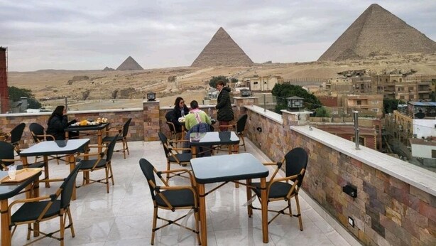 An outdoor dining area with tables and chairs, overlooking the pyramids. - Sky pyramids  (Giza)