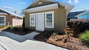 A single-story house with a front porch, a small garden area, and a clear sky. - "Live Oak" Cottage Reidsville Georgia (Reidsville)