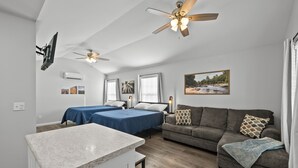 A compact, well-lit room with two beds, a sofa, a ceiling fan, and a small kitchen area. - "Live Oak" Cottage Reidsville Georgia (Reidsville)