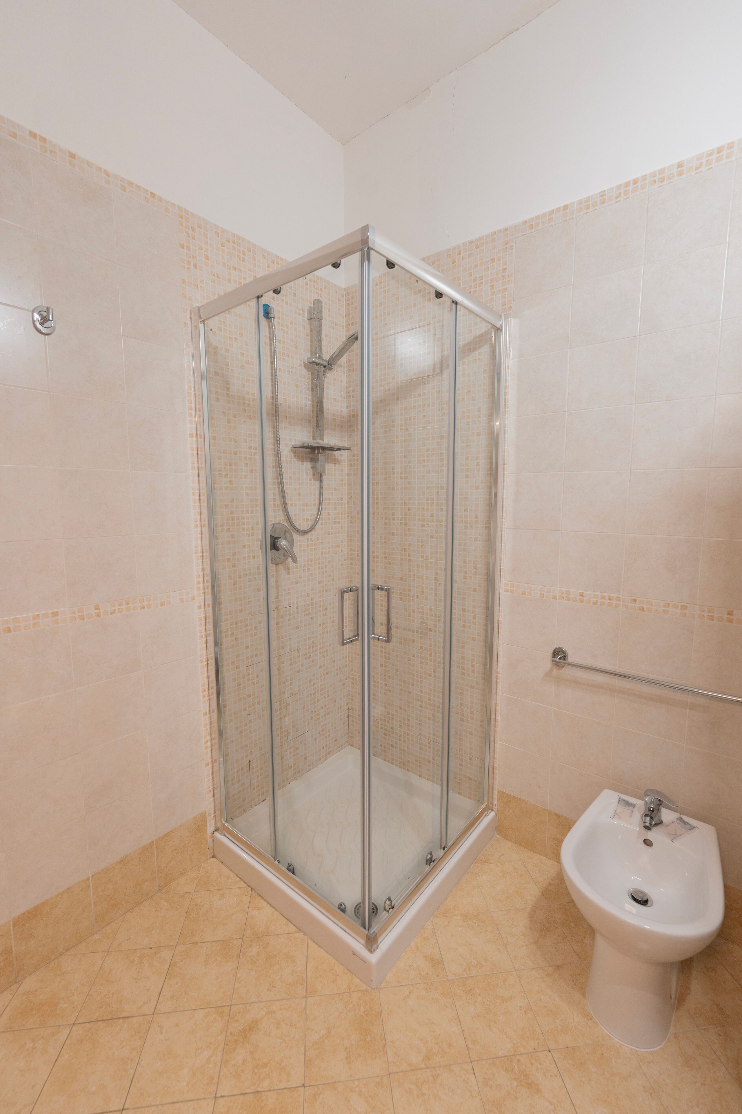 Ein Badezimmer mit Duschkabine, Waschbecken und Fliesenwänden.