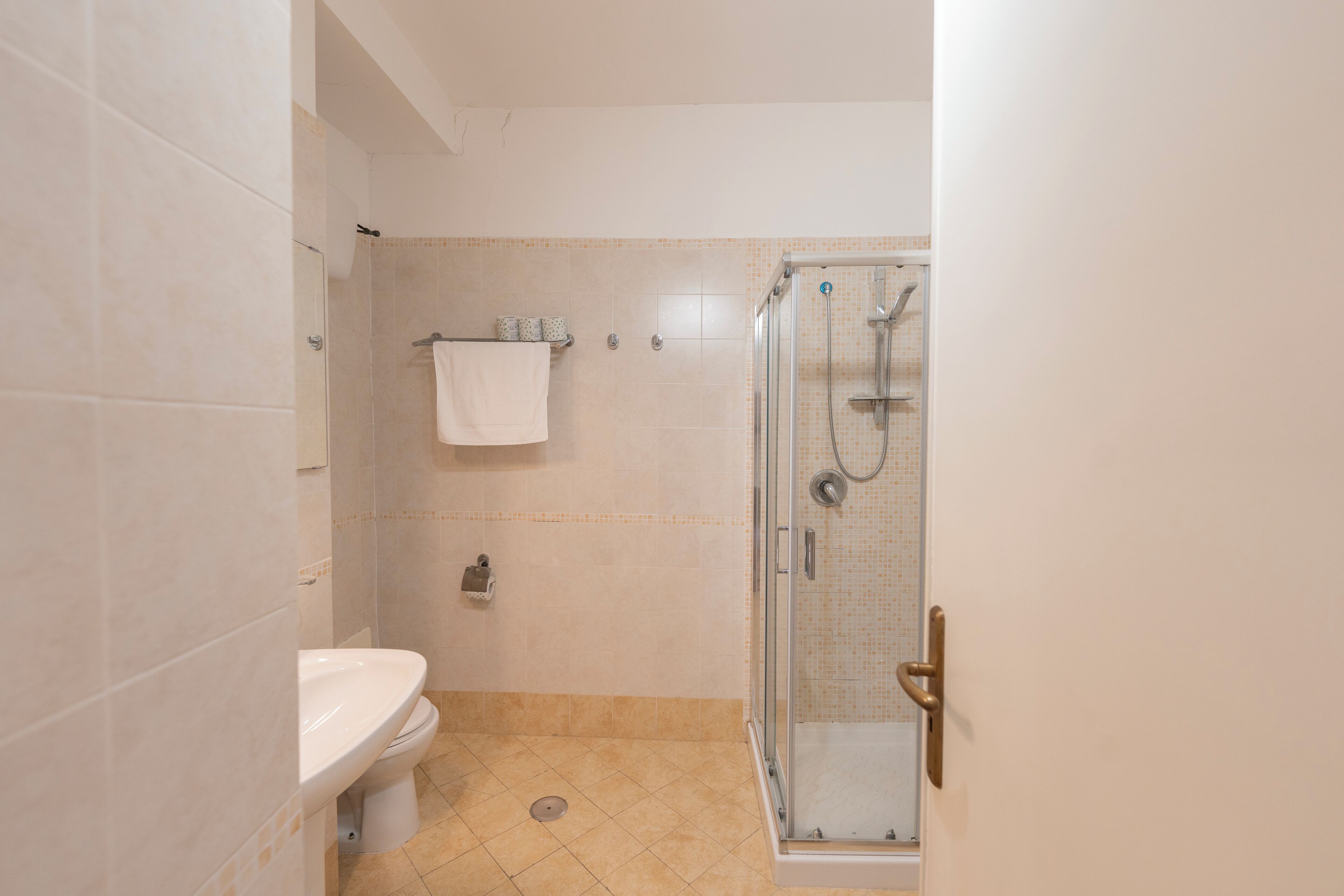 A bathroom with a toilet, a shower with a glass door, and a towel rack.