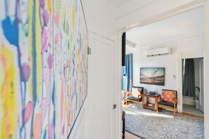 Habitación de hotel con un cuadro abstracto grande, vista a la playa y una zona de estar acogedora con alfombra.