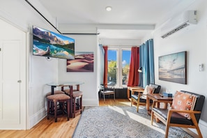 Una sala moderna con un televisor de pantalla plana grande, un comedor con mesa de vidrio y una zona de estar acogedora.