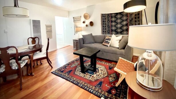 A living room with a sofa, coffee table, dining table, chairs, and a rug. - Central Craftsman Apartment (Arcata)
