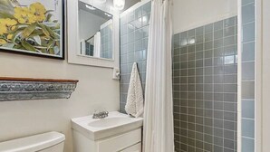 A bathroom with a white sink, a mirror, and a shower with grey tiles. - Central Craftsman Apartment (Arcata)