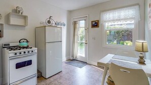 Une cuisine équipée d’une cuisinière, d’un réfrigérateur et d’une table à manger avec une lampe.
