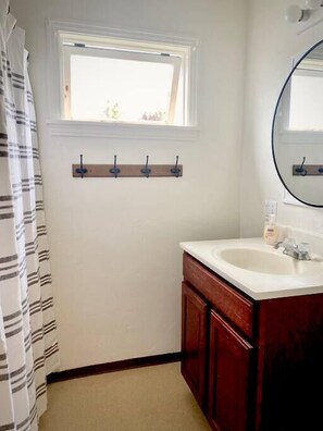 Bathroom features a sink, mirror, and striped shower curtain.