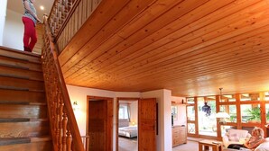 A wooden interior with a staircase, a living room with a sofa, and a bedroom with a bed. - Upper mill (Sohland an der Spree)