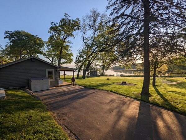 A house with a covered porch, a lawn, and a view of a lake.