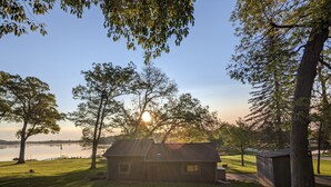 A house with a sloped roof, surrounded by a well-maintained lawn and trees. - Dogs Stay Free!  Lakefront Bungalow with Dock (Juneau)