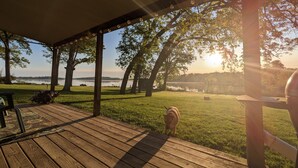 A wooden deck with a covered area, a grill, and a grassy lawn with trees. - Dogs Stay Free!  Lakefront Bungalow with Dock (Juneau)