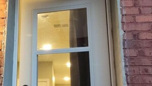 A white door with a small window and a doorbell.