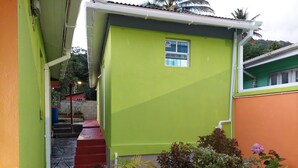 A green building with a small window, a red staircase, and potted plants. - Salz Cozy Inn. Comfort at it's best. Peace is guaranteed! (Roseau Valley)