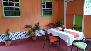 A room with a table and chairs, potted plants, and windows with green frames. - Salz Cozy Inn. Comfort at it's best. Peace is guaranteed! (Roseau Valley)